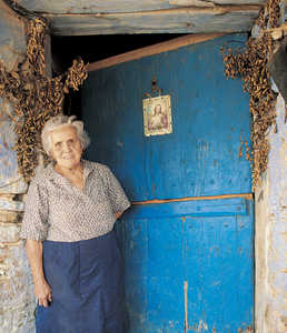 98.	Mara Manterola outside the door of Aranburu Zahar farmhouse (Aia), protected by the branches of San Juan and a modern image of the Sacred Heart of Jesus.