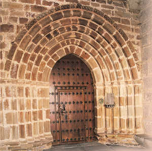 66. The doorway of the church in Abaltzisketa is formed by six pointed archivolts. The paired columns have capitals with signs and the classical chequered pattern. The spiral work of the outer arch has a zigzag decoration.© Jonathan Bernal